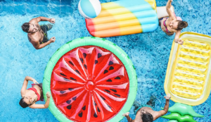 four friends take antioxidants and play water volleyball with assorted pool floats